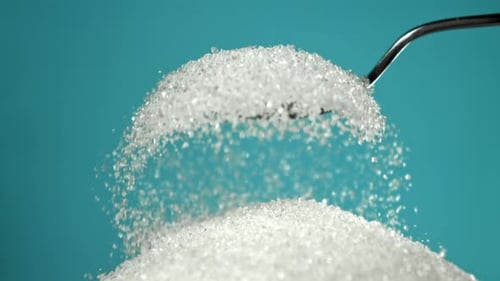 Sugar Pours Out of a Spoon on a Blue Background Filmed on a Highspeed Camera at 1000 Fps