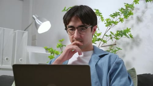 Young caucasian man planning project or using artificial intelligence on laptop in home office.
