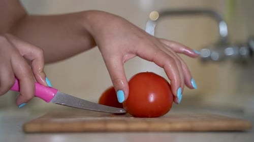 Woman Cutting Fresh Tomato in Kitchen