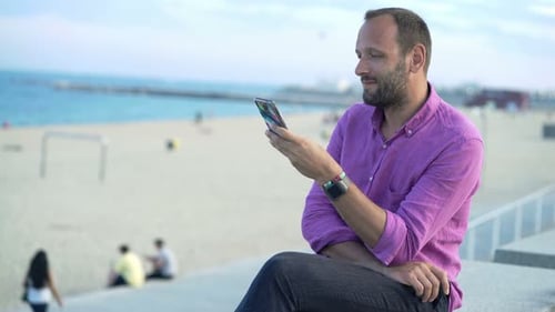 Young Man Texting on Beach Promenade