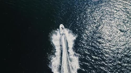 Drone Shot of a Motorboat Cruising at Speed Over the Blue Sparkling Ocean