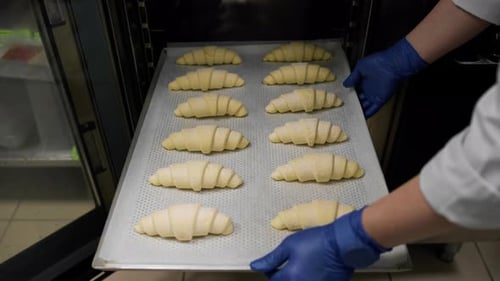 Kitchen in a bakery - the chef sends a baking sheet with croissants to the combi oven