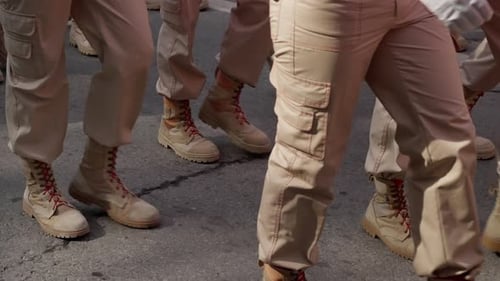 Closeup View of Uniformed Individuals Marching in Synchronized Formation on a Paved Surface Focusing