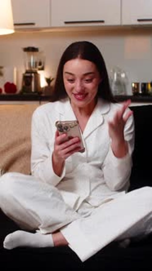 Excited Woman in Pajamas Using Phone at Home