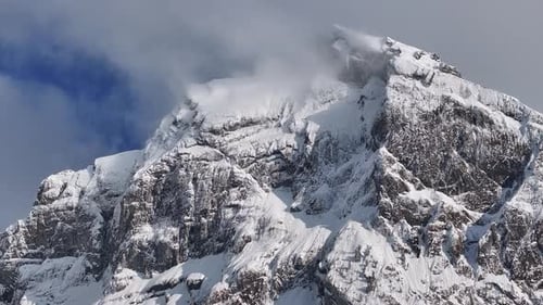Vista aérea del escarpado pico cubierto de nieve de Fronalpstock bajo un cielo parcialmente nublado en Glarus Nord, Suiza