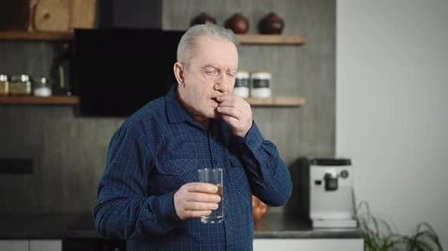 Senior Man Taking Pill with Water Indoors