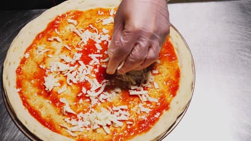 Man Adds Grated Cheese on Pizza Base with Sauce Closeup