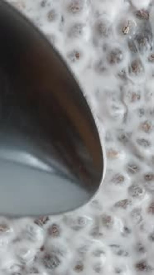 Vertical video. Dessert Made From Soaked Chia Seeds. I Spread Them With A Spoon. Top View, Close-Up.