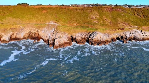 Waves crash against rocky shoreline at a coastal area.