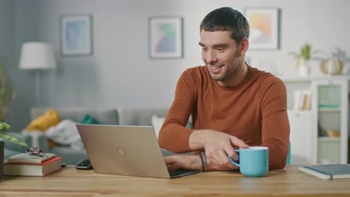 Man Works On Laptop, Drinks Coffee at Home