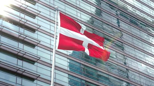 Waving Red Flag with White Cross on Modern Building