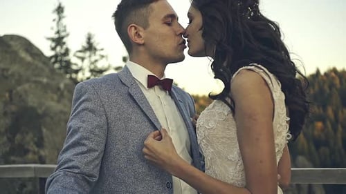 Evening Sun Illuminates the Rocks Where Wedding Couple Kisses