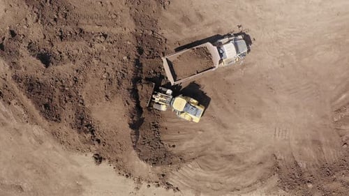 Excavator loading soil onto a Truck, Aerial view.