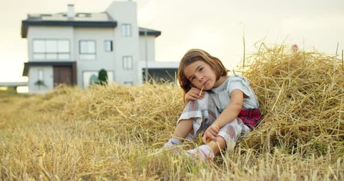 The Girl is Dreaming with Her Thoughts on the Field in the Hay