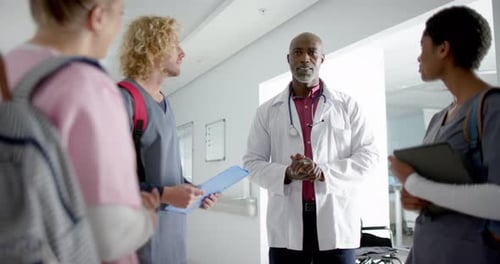 Diverse doctors discussing work in corridor at hospital, slow motion