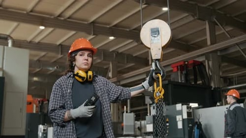 Jeune femme opérateur de grue posant sur le sol de l'atelier de fabrication métallique