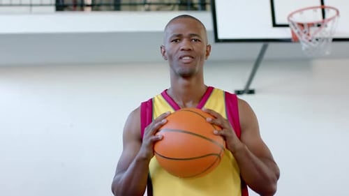 African American man holds a basketball in a gym