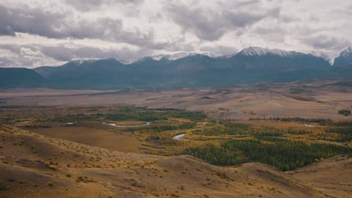 Sweeping Panorama Reveals a Vast Valley Adorned with a Winding River Framed By Snowcapped Mountains