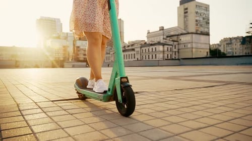 Ein modernes Mädchen reitet in den Sonnenuntergangsstrahlen durch die Stadt