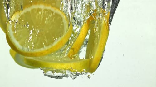 Lemon Slices Dropping into Water Refreshing Beverage