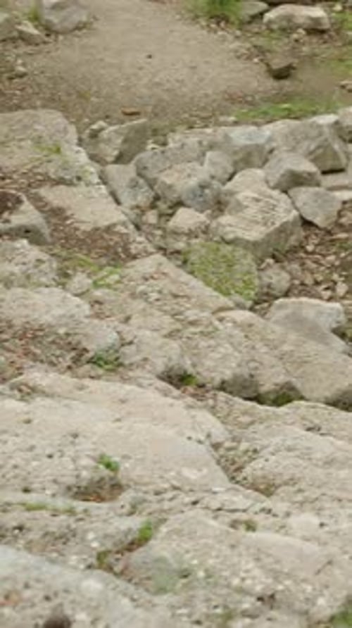 Woman Sits Among Ancient Ruins in Landscape Shot