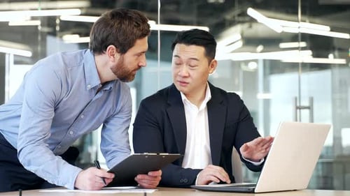 Businessmen Collaborate Using Laptop in Modern Office