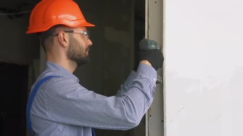 Construction Worker Drills Wall Using Power Drill