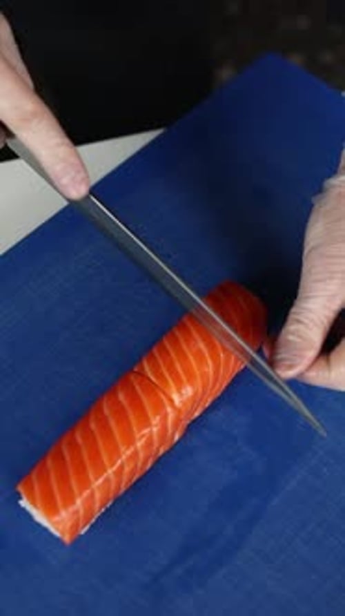 Chef in white gloves prepares salmon rolls