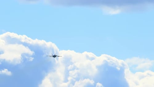 Jet Airplane Flying Past Fluffy White Clouds