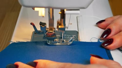 Closeup in a Sewing Workshop on a Machine the Seamstress Master Makes Cut on a Blue Fabric
