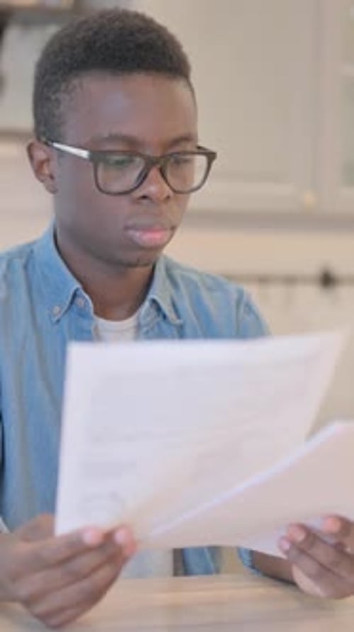 Young Man Reads Documents at a Wooden Table