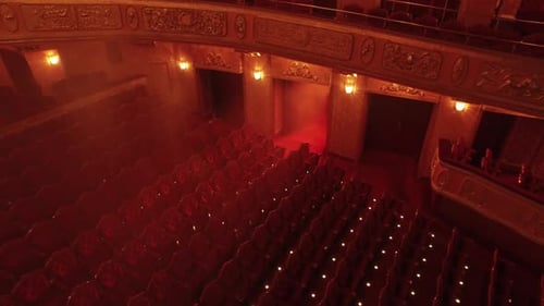 Aerial shot with a theatre lit up by red lights and misty