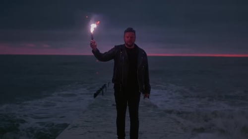 Person Standing on Pier Holding Flaming Torch