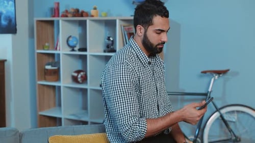 Nahaufnahme seriöser attraktiver junger Mann benutzt Telefon, sitzt auf dem Sofa, Hausportrait, Smartphone-Hände