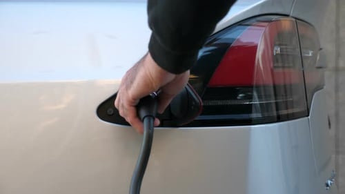 Hand Removes Charger from Electric Car Charging Port