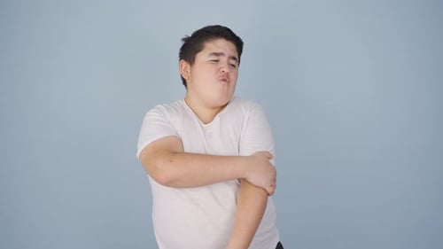 Teen Boy Scratching An Itchy Arm In Studio