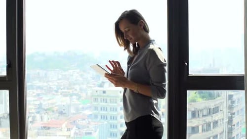 Woman Using Tablet Computer by Bright Apartment Window