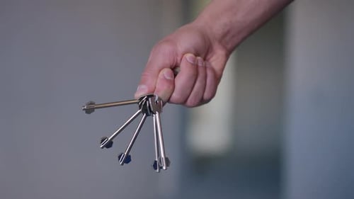 Closeup New Flat Key in Male Caucasian Hand Turning Showing Off Real Estate Ownership
