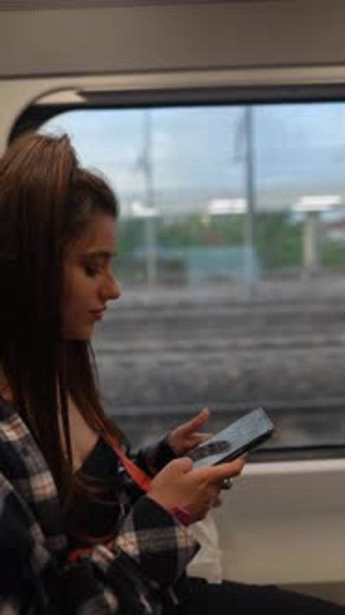 Eine junge Frau in einem Zug ist in ihr Smartphone vertieft und genießt ihre digitale Unabhängigkeit