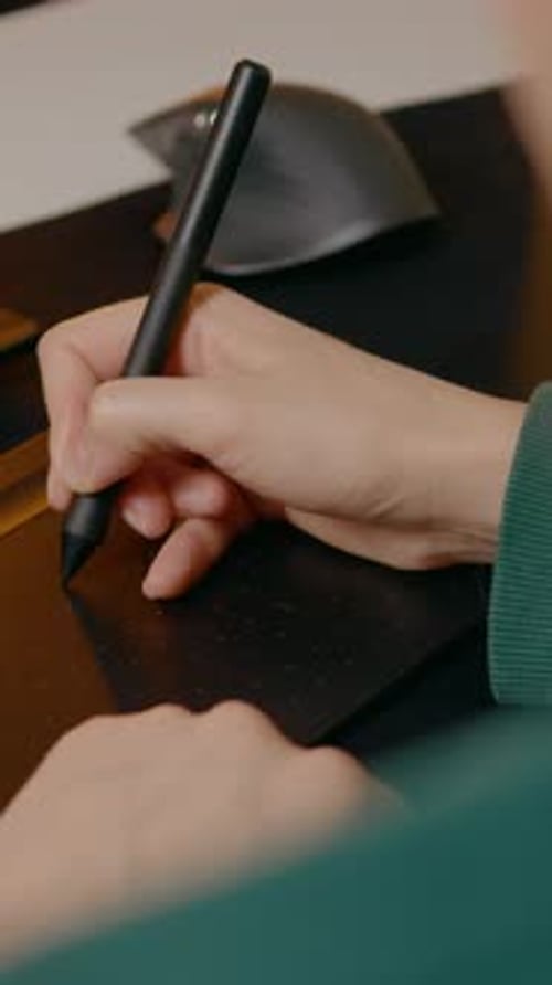 Hand using stylus on graphics tablet at desk