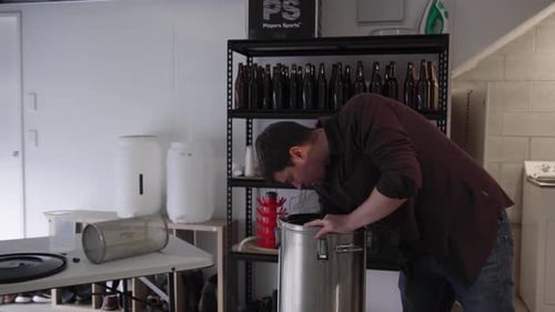 Um homem instalando um equipamento de chaleira na garagem, uma cervejaria artesanal
