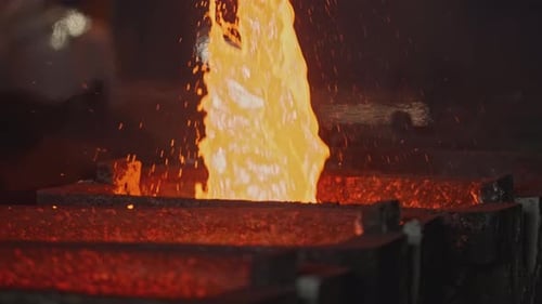 Die Grube gießt flüssiges Metall in Formen, Stock-Bildmaterial, flüssige Masse geschmolzenen Metalls fließt aus dem Grubenstrom