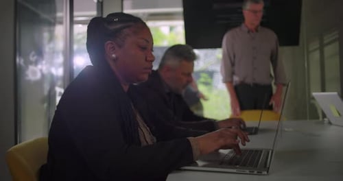 Diverse Team Collaborating on Laptops in Modern Office