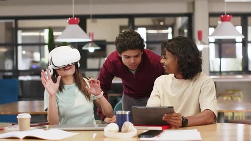 African American peers testing VR at study table, tablet user starting demo, headset user gesturing