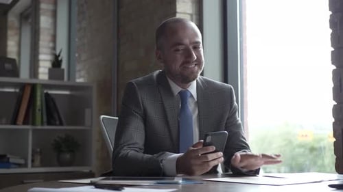 Smiling Businessman with Smart Phone and Paperwork in Office Adult