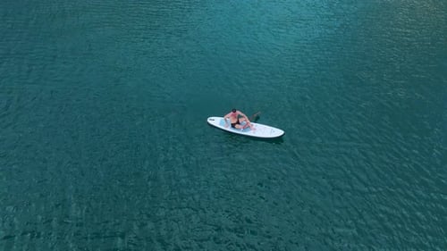 Aerial View Friends Paddleboard on Emerald Waters Framed By Striking Peaks and Surreal Dry Trees