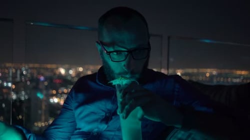 Sad, Unhappy Man Drinking Cocktail Sitting on Terrace in Bar at Night Alcohol