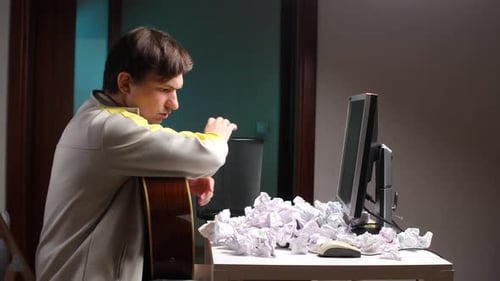 Young Man With Guitar and Crumpled Paper