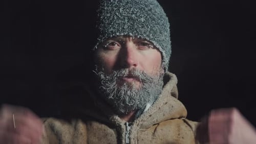 Un homme au visage gelé. Un jeune homme adulte à la barbe glacée et au chapeau respire à l'extérieur à une température inférieure à zéro