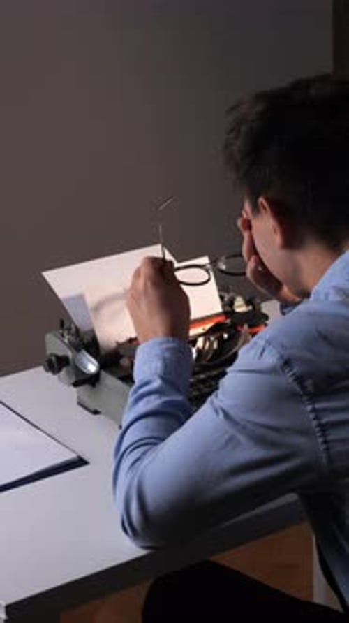 Young Man Types on Vintage Typewriter at Desk